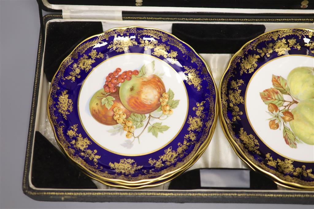 A cased dessert service containing six gilt and fruit decorated plates and a set of knives and forks